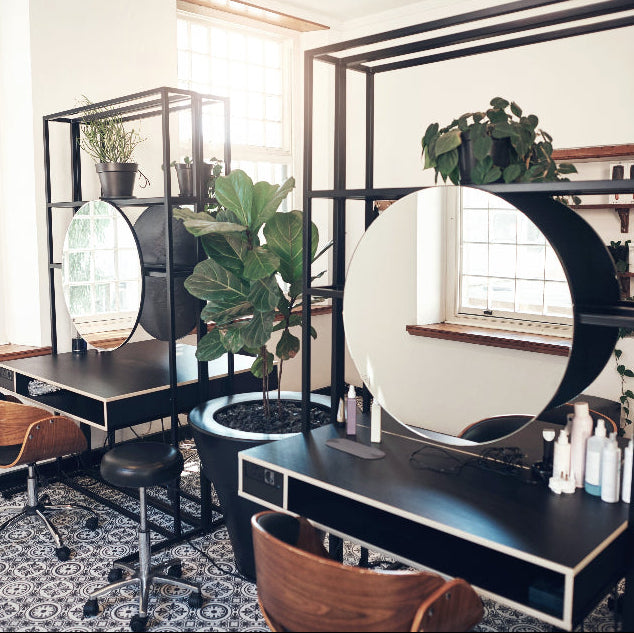 Modern professional salon workstations with large styling mirrors and integrated storage in a luxury Australian hair salon