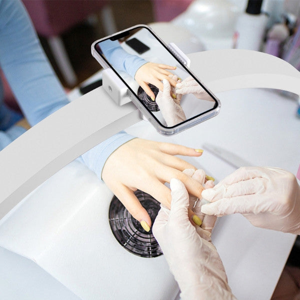 Professional nail technician using the integrated phone holder on the Arch LED lamp to record a manicure