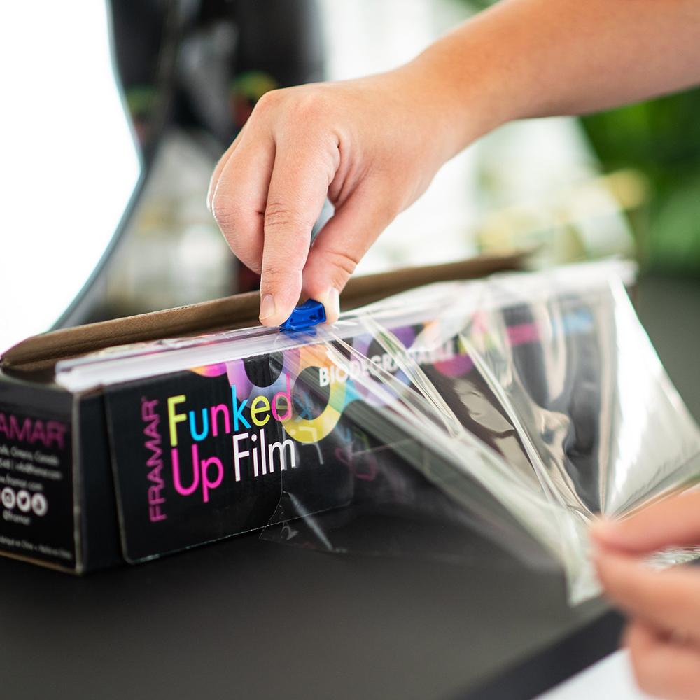 Professional stylist using the built-in slider cutter on the Framar Funked Up Film box for precise sectioning