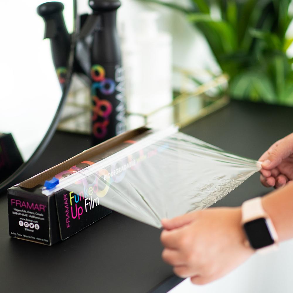 Stylist pulling transparent Framar Funked Up Film showing the pliable zero-cling material for hair colour protection