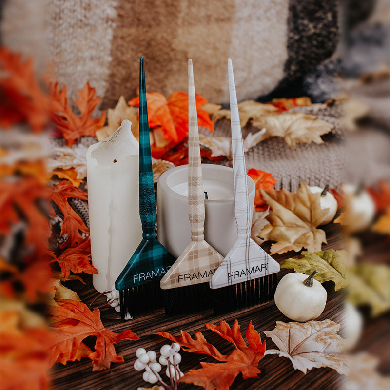 Teal, white, and tan plaid Framar Big Daddy hair colour brushes displayed with autumn leaves and candles
