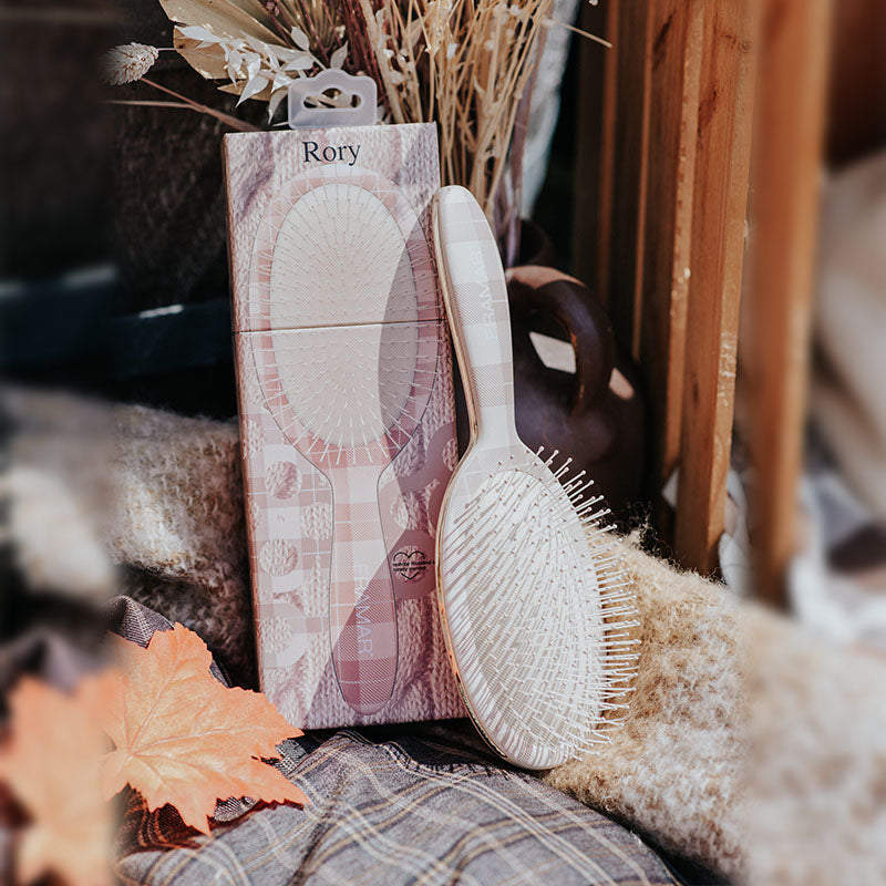 Professional tan plaid Framar Rory detangle brush leaning against salon packaging