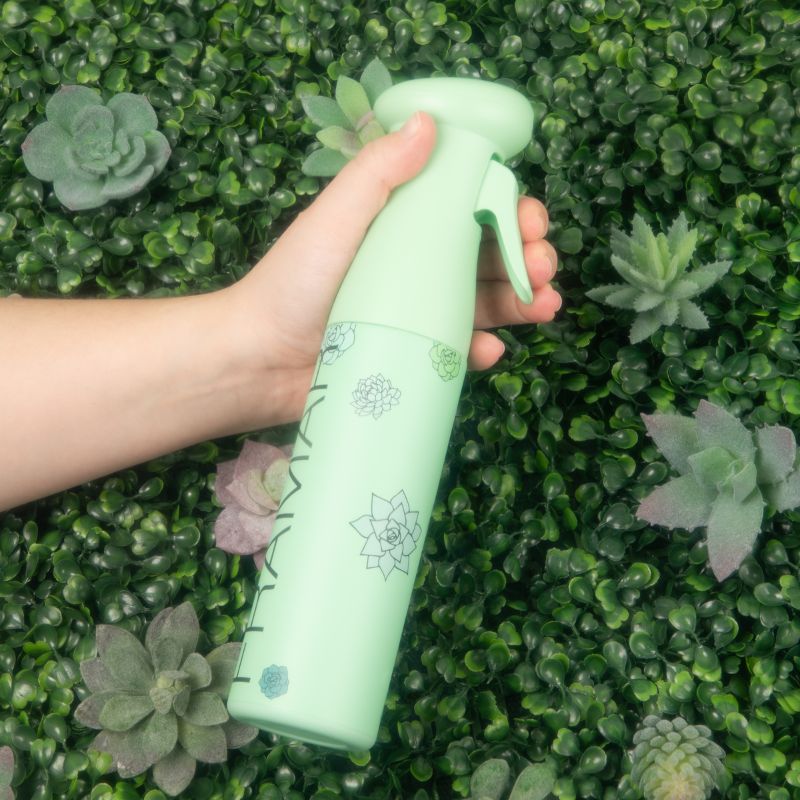 Hand holding the Framar Plant Mom Myst Assist spray bottle against a greenery background to show ergonomic grip