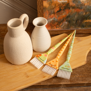 Framar Quilted Triple Threat brushes on a wooden board next to salon décor