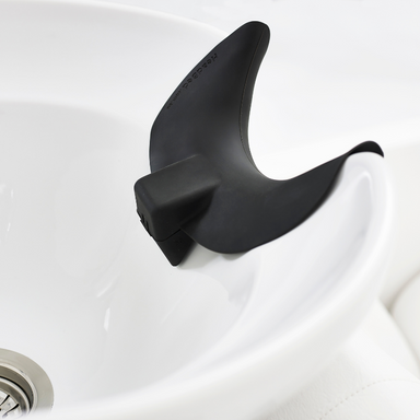 Top view of the black HeadBed ergonomic support cushion attached to the edge of a white ceramic salon basin