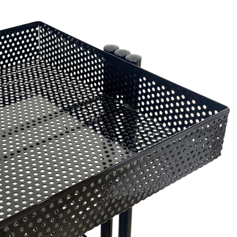 Close up of the black perforated metal storage basket on the Joiken Clem salon trolley