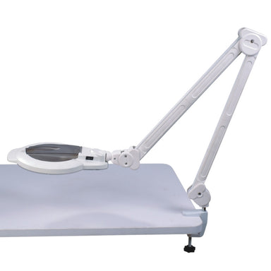 Full view of the Joiken Opal 262 LED magnifying lamp with adjustable swing arm and table clamp mounted on a white desk