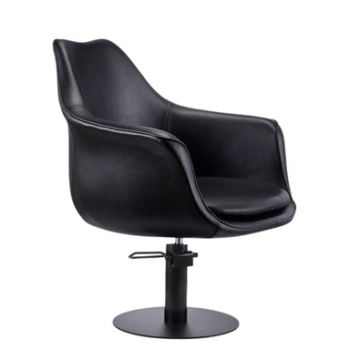 Side profile of the black Karma Cronulla salon chair showing the curved armrests and hydraulic base