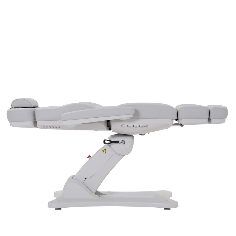 Side profile of the white Karma Inglewood electric treatment table in a flat position showing the heavy-duty base