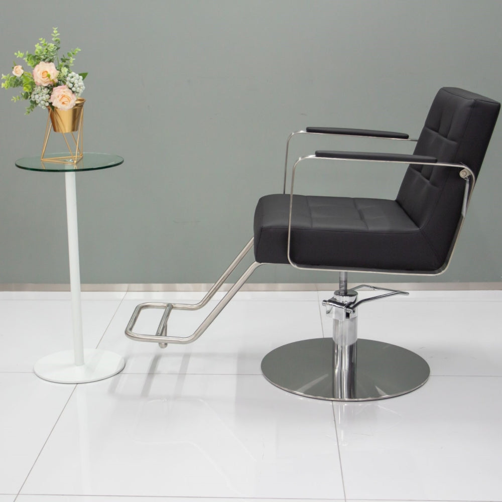 Side profile of the Karma Lithgow salon chair highlighting the metallic armrests and hydraulic lift height