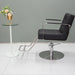 Side profile of the Karma Lithgow salon chair highlighting the metallic armrests and hydraulic lift height