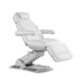 Fully adjustable electric beauty treatment chair in white with tilted backrest and leg rest