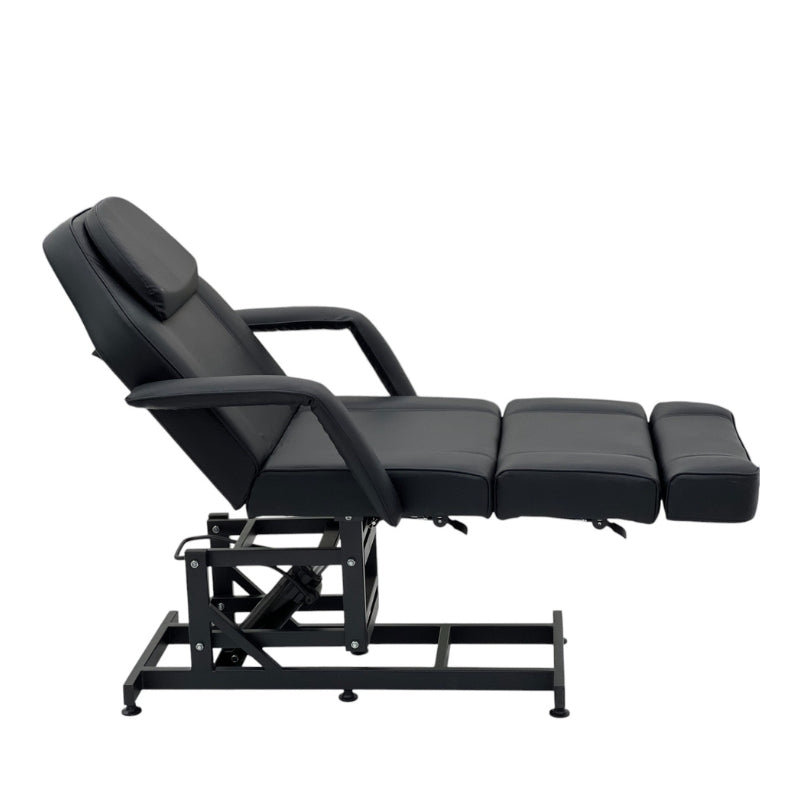 Side profile of the black Karma Taupo hydraulic beauty bed showing the heavy duty base frame