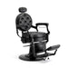 Black upholstered barber chair with adjustable footrest and armrests