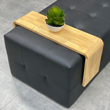 Wooden ottoman slide over table positioned on black ottoman in salon waiting