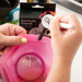 Stylist writing a colour formula onto a Framar Formula Friend clip attached to a pink mixing bowl using the dry erase marker